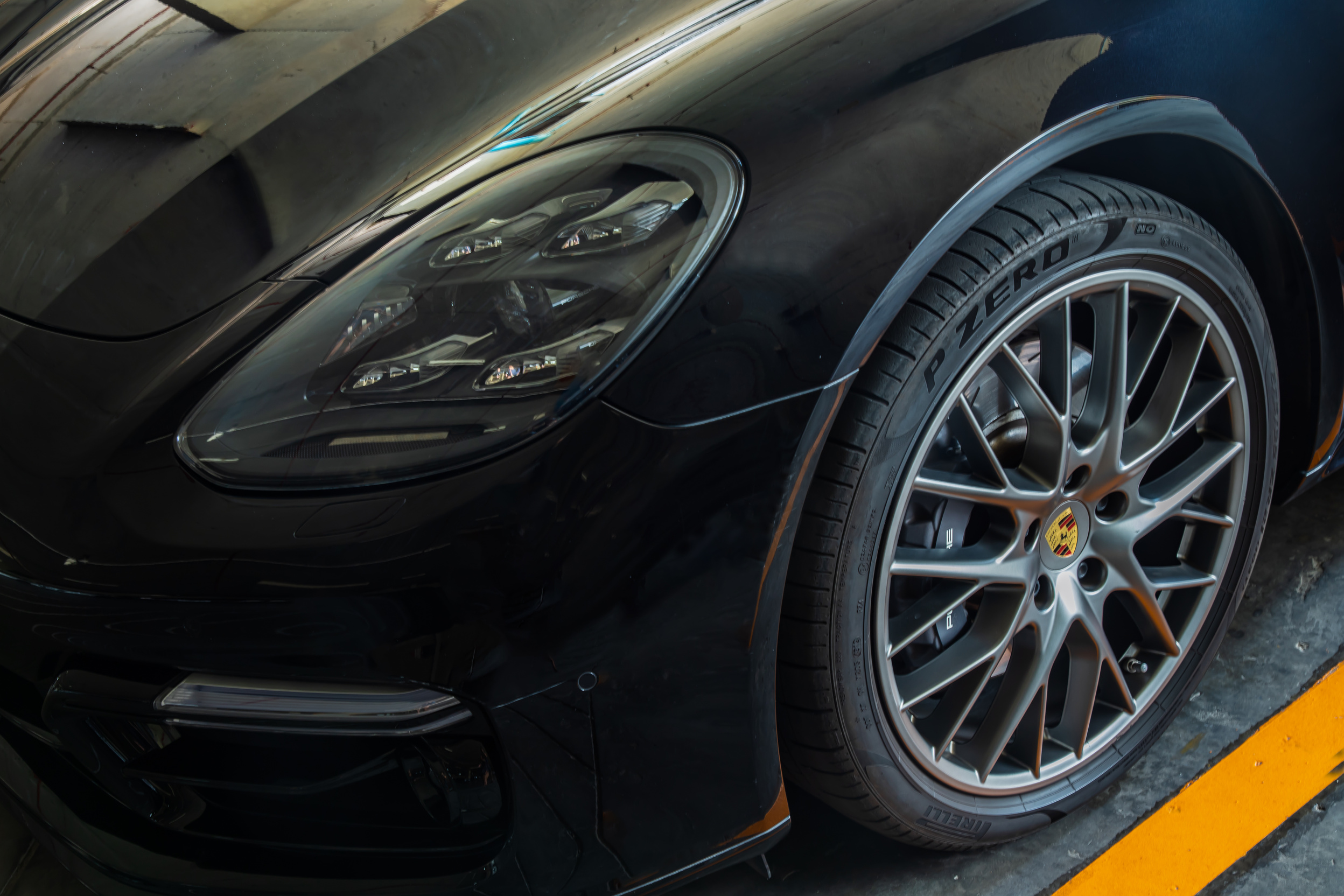 Close-up of Headlights, Wheel, and Rim of Black Porsche Sports C